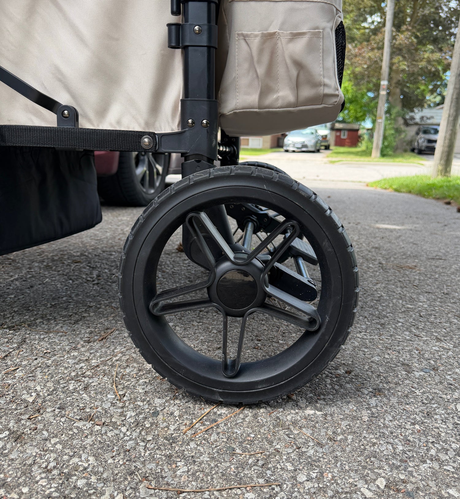 Close-up of a stroller wheel on a sidewalk with a blurred background